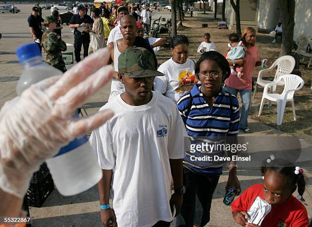 Volunteer offers water to evacuees lined up to receive their FEMA debit cards at Reliant Arena, near the Astrodome September 9, 2005 in Houston,...