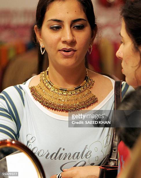 Visitor takes advice from her friend about a gold necklace she wears, designed by an Indian jeweler, at an exhibition in Bangkok, 10 September 2005....