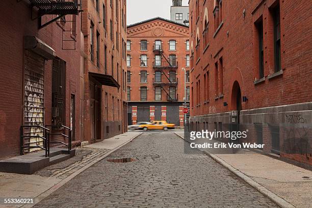 cobblestone alley in tribeca with taxi passing by - straat stockfoto's en -beelden