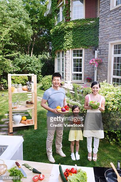 a family of three with vegetables in the outdoor kitchen - asian mother and daughter pumpkin stockfoto's en -beelden