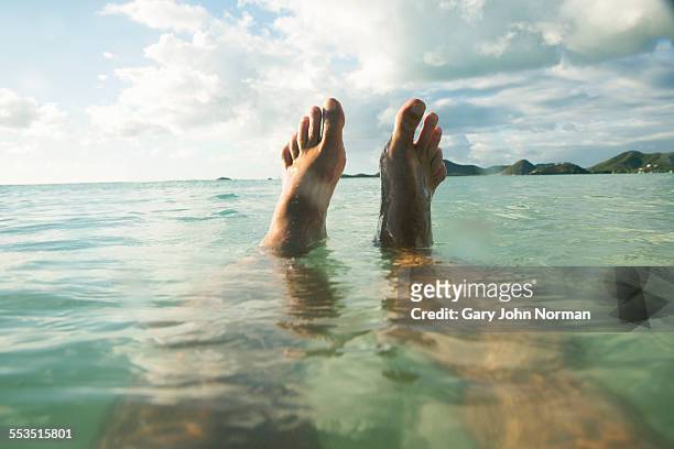 pov man floats in tropical sea, feet out of water - feet fotografías e imágenes de stock