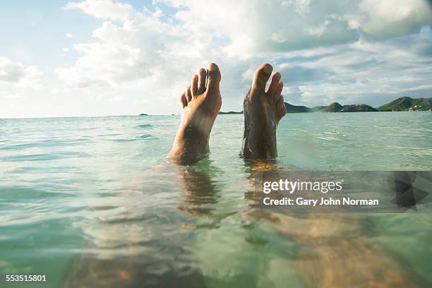 pov man floats in tropical sea, feet out of water - his foot imagens e fotografias de stock