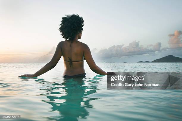 young black woman wading into ocean, rear view. - vadear imagens e fotografias de stock