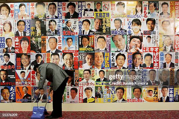 Hotel employee cleans the floor in front of Democratic Party of Japan campaign posters at a Tokyo hotel uses to hear election results September 11,...