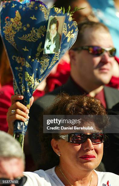 An unidentified woman holds up a bouquet of flowers, with a photograph attached to it, as she mourns at Ground Zero September 11, 2005 in New York...