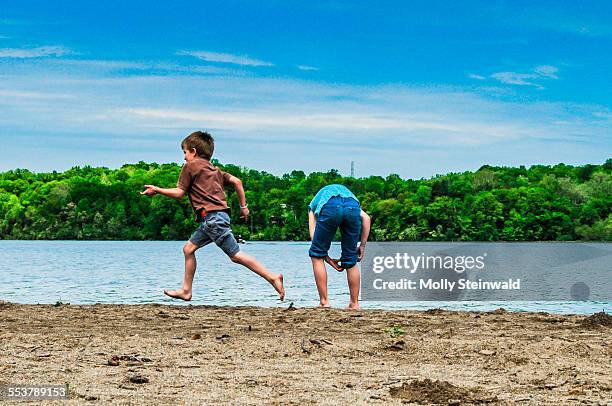 a boy runs by a girl at the waters edge at hueston woods state park oh. - molly steinwald stock pictures, royalty-free photos & images