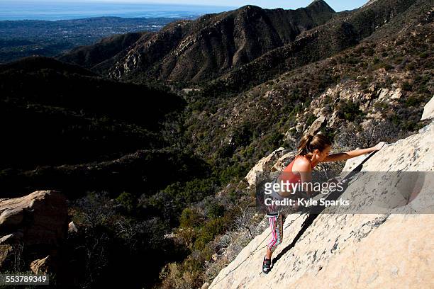 a woman wearing a red tank top and striped pants climbs the rapture (5.8) on lower gibraltar rock in santa barbara, california. - rock climber bildbanksfoton och bilder