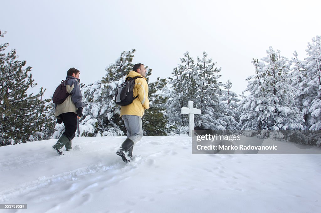 Hikers on a mountain top with a cross in front of them