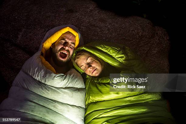 man and a woman in sleeping bags while kevin yawns. - sleeping bag stock pictures, royalty-free photos & images