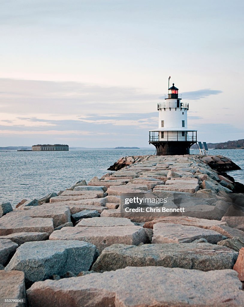 A lighthouse stands guard over the entrance to a harbor.