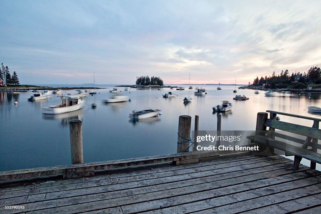 Boats gently rock in the tide along the Maine Coast at sunset.