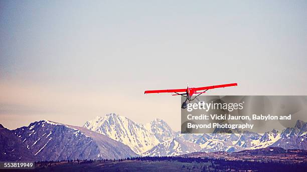 red float plane against blue mountains - alaska - red plane stock pictures, royalty-free photos & images
