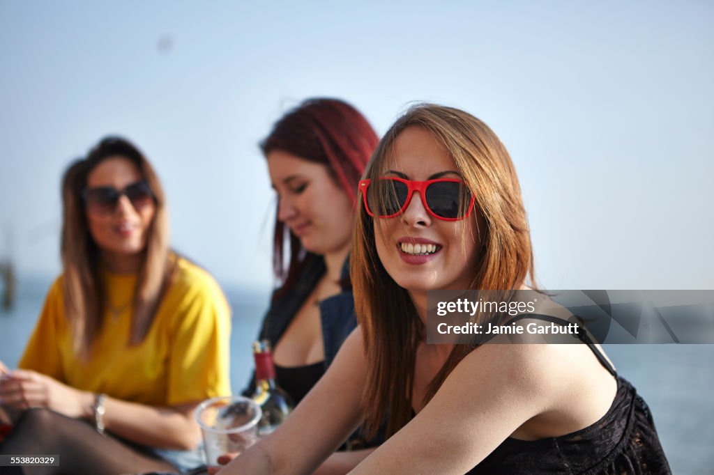 Three mid 20s females sat together on the beach