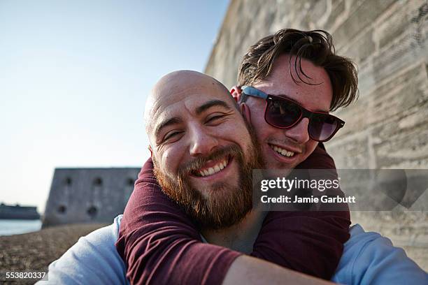 bearded bald male smiling whilst being hugged - portsmouth england stock-fotos und bilder