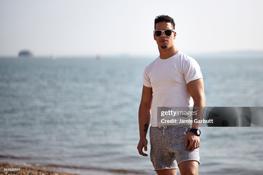 A mid 20's mixed race male stood on a beach