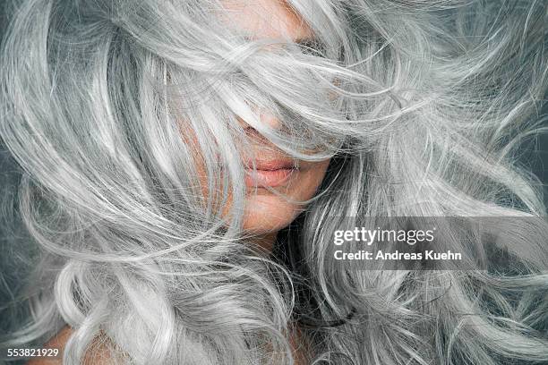 woman with grey hair blowing across her face. - hair color foto e immagini stock