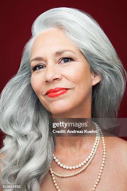 woman with long, grey hair wearing pearls. - rode lippenstift stockfoto's en -beelden