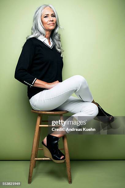 stylish woman with grey hair sitting on a stool. - sgabello foto e immagini stock