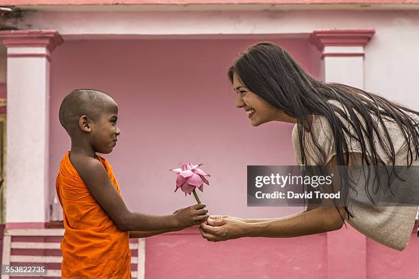 young buddhist monk giving lotus flower to tourist - generosidad fotografías e imágenes de stock