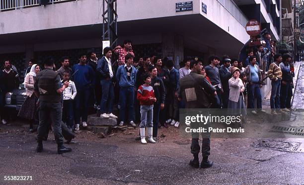Crowd stands behind soldiers as they look upon the destruction and damage at the scene of the suicide bombing of the American Embassy, Beirut,...