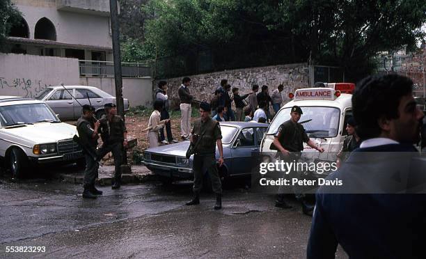 Military personnel stand guard as ambulances pass by amid the destruction and damage at the scene of the suicide bombing of the American Embassy,...