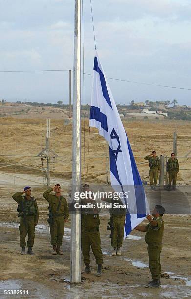 Israeli soldiers raise their national flag at the just-locked border gate after the last troops withdrew through the Kissufim crossing between Israel...