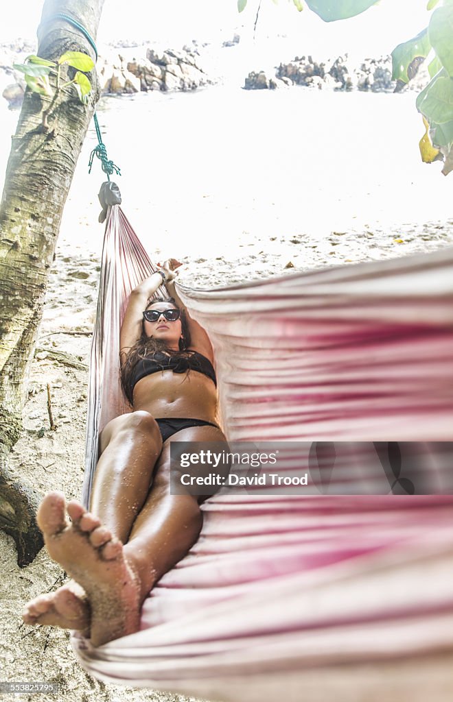 Young woman relaxing in pink hammock.