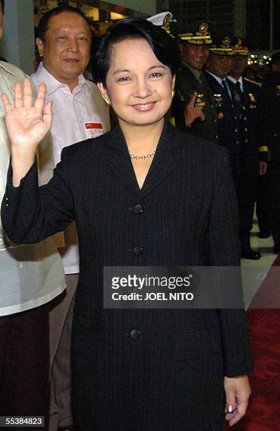 Philippine President Gloria Arroyo waves to photographers at Manila International Airport, 12 September 2005, as she prepares to depart for New York...