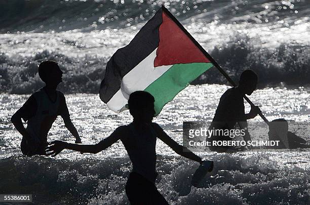 Palestinian boys play with their national flag on a beach near the former Israeli settlement of Neve Dekalim 12 September 2005. Thousands of...