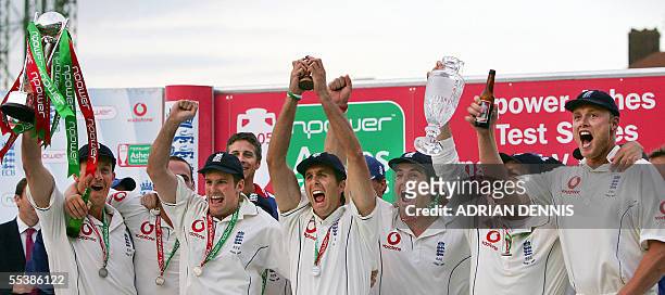 London, UNITED KINGDOM: England's captain Michael Vaughan holds aloft the replica of the Ashes trophy flanked by teammates after defeating Australia...