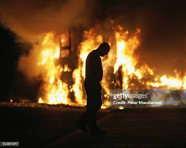 Man walks past a burning bus in a Loyalist area on September 12, 2005 in Belfast, Northern Ireland. The clashes have continued for a third day after...