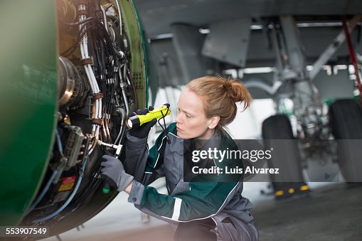 Engineer using flashlight to analyze airplane part Engineer using flashlight to analyze airplane part
