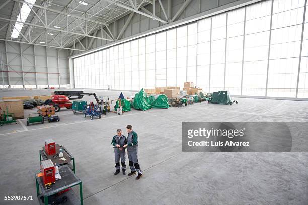 Engineers using digital tablet in hangar