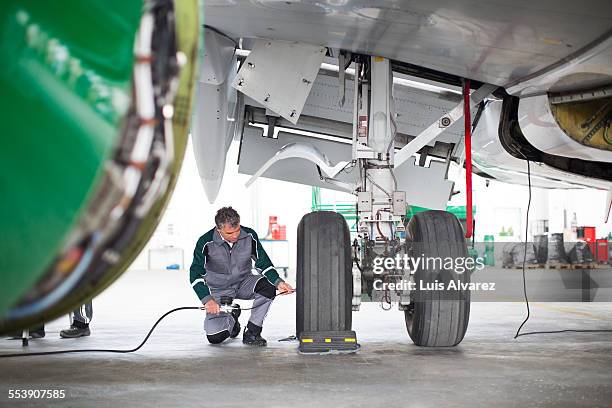 engineer inspecting aircraft tires in hangar - landing gear stock-fotos und bilder