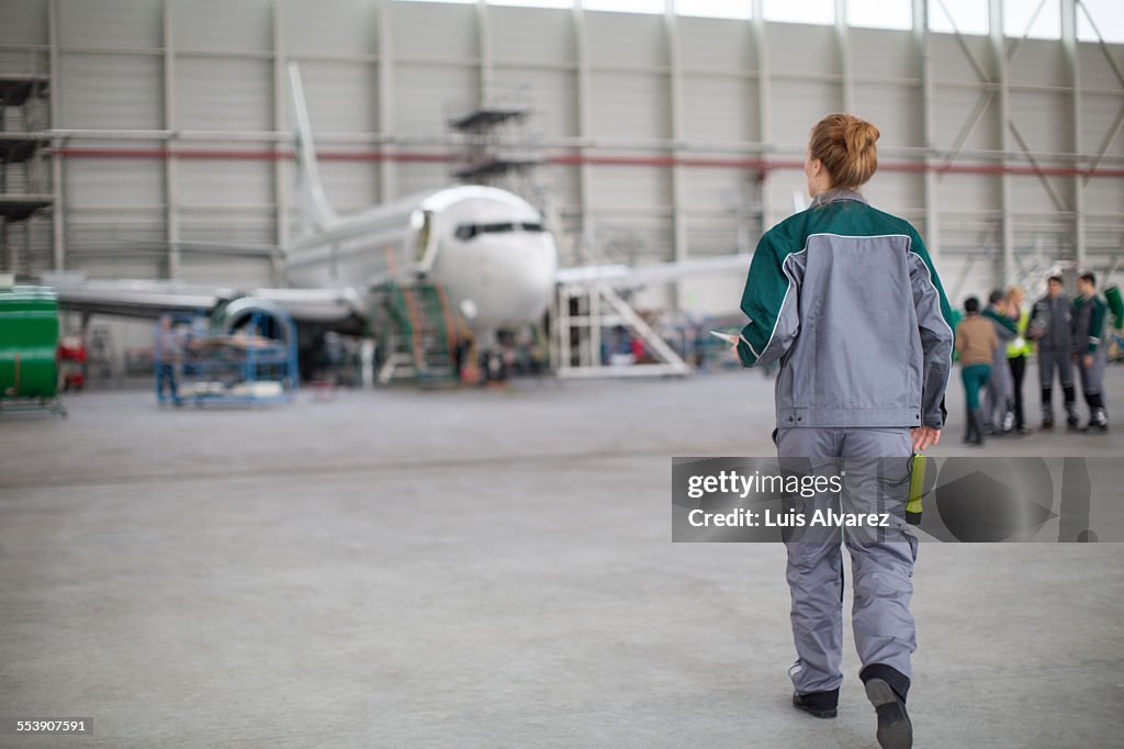 Female engineer walking towards aircraft