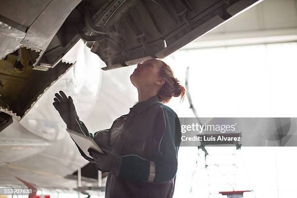 female engineer inspecting airplane in hangar - aviation engineering stockfoto's en -beelden