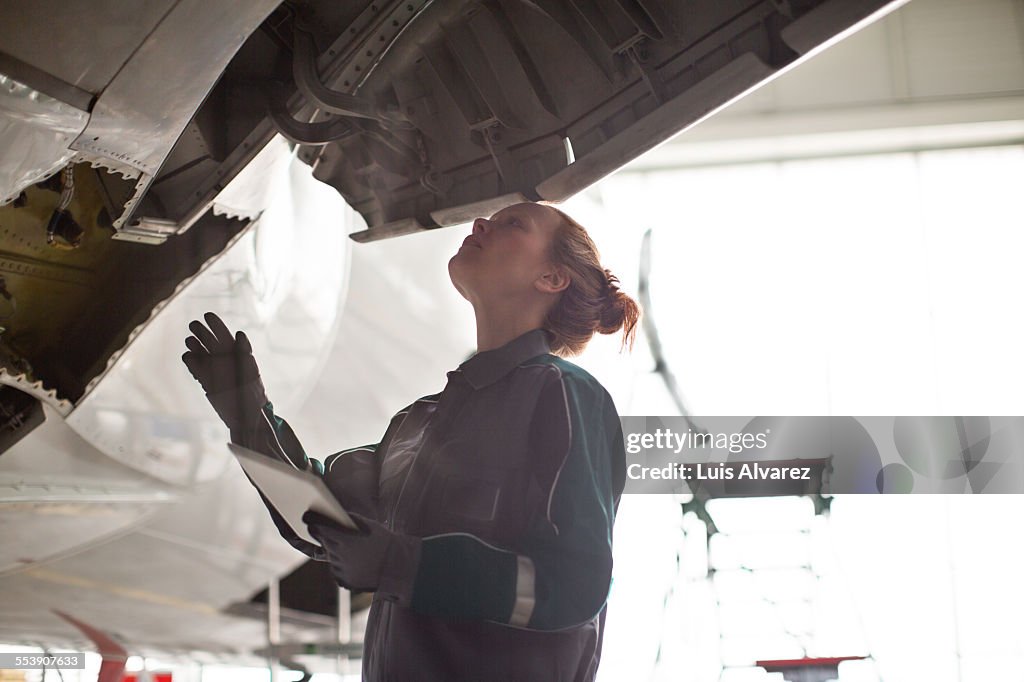 Female engineer inspecting airplane in hangar