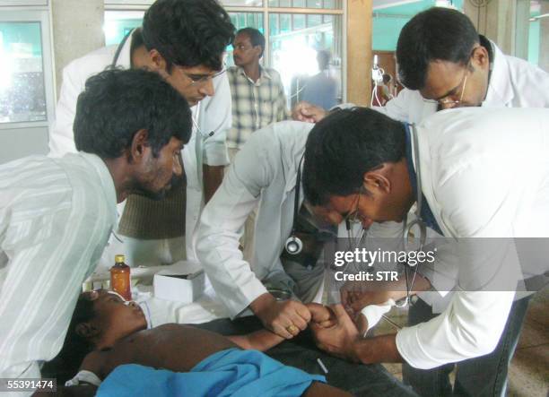 Indian doctors and medical staff are watched by an anxious father as they administer aid to a child suffering from Japanese Encephalitis in a ward of...
