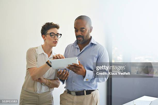 coworkers scrolling on digital tablet - office holding sign stockfoto's en -beelden