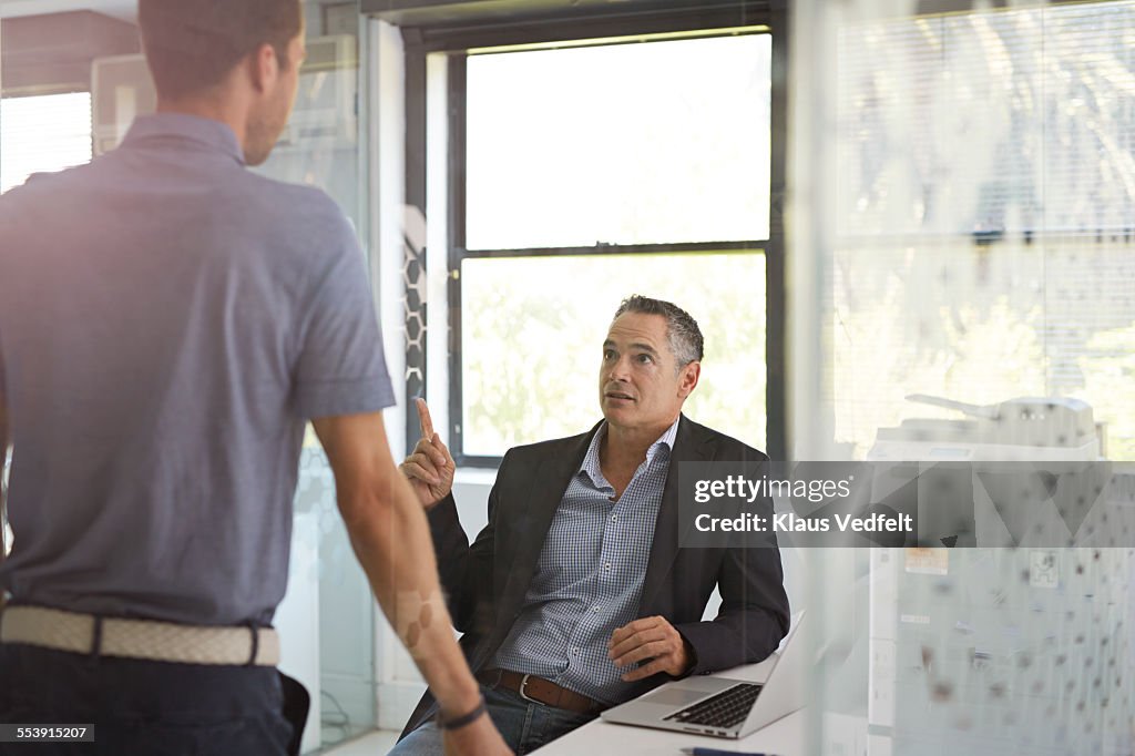 Businessman at office explaining to coworker