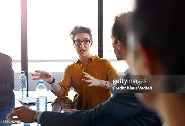 businesswoman explaining to coworkers at meeting - speaking explaining young woman stock-fotos und bilder