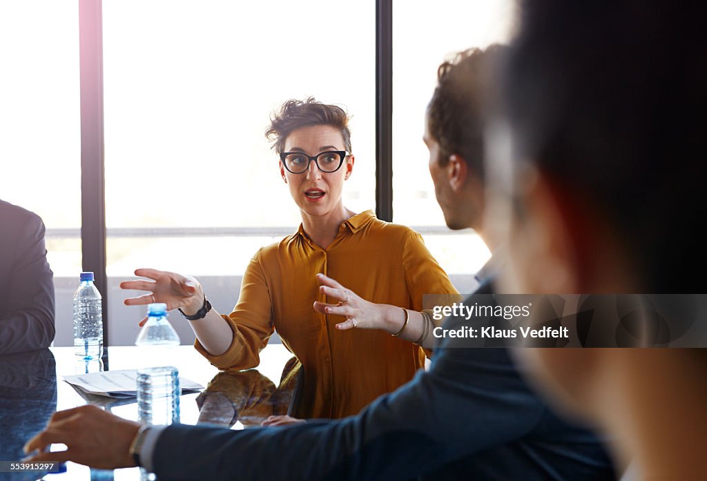 Businesswoman explaining to coworkers at meeting