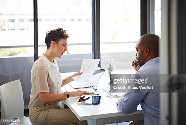 coworkers having discussion holding papers - papierkram stock-fotos und bilder