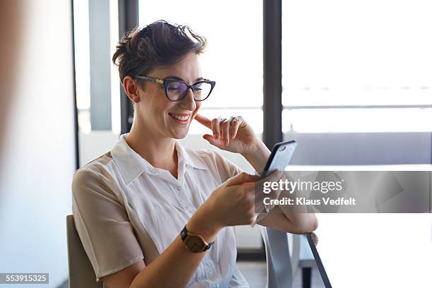 cool businesswoman looking at phone and laughing - friendly business phonecall stockfoto's en -beelden