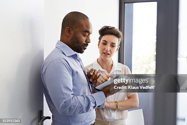 coworkers looking at tablet together - personas de negocios fotografías e imágenes de stock