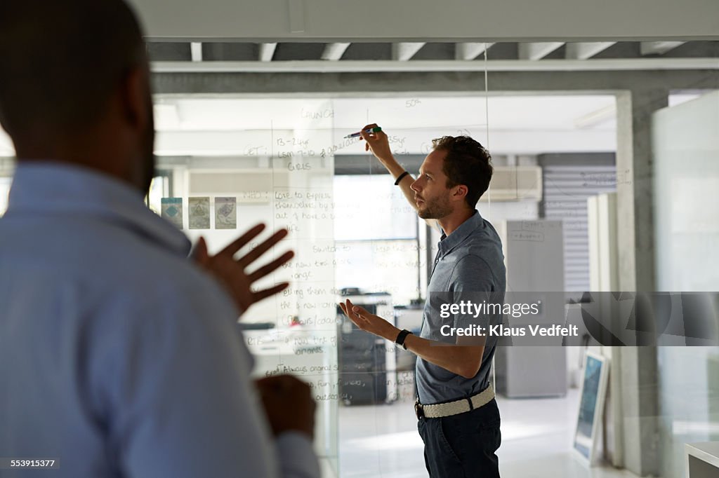 Businessmen going threw strategy on glass wall