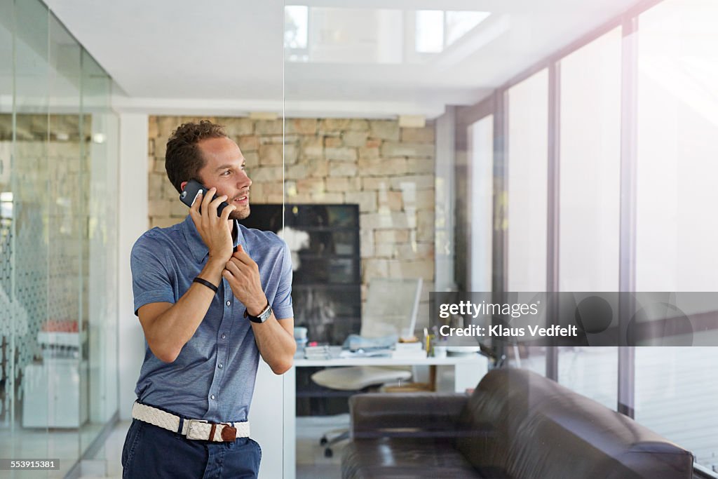 Businessman standing in office, talking on phone