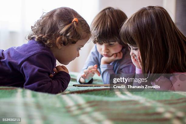 kids using a digital tablet - three people in bed stock pictures, royalty-free photos & images