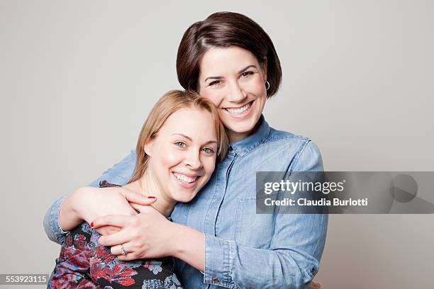 lesbian couple hugging and smiling - brown hair on white stock pictures, royalty-free photos & images