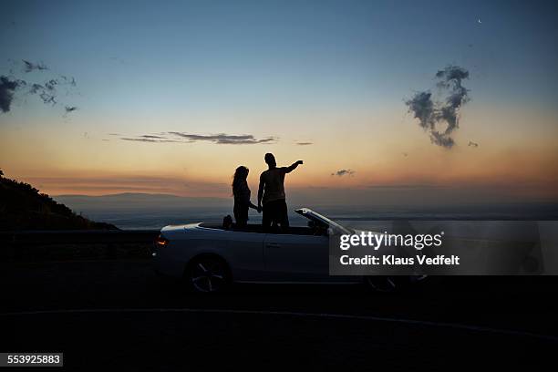 couple holding hands and looking at sunset - wanderlust concept fotografías e imágenes de stock